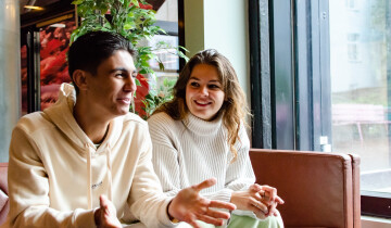 Two students laughing in a sofa